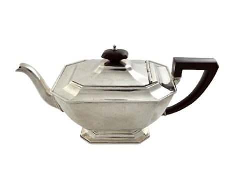 A silver teapot of cut cornered rectangular tapering form, in the Art Deco taste, having brown composition fittings, monogram