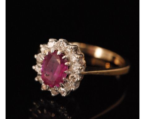 A 9ct hallmarked ruby and diamond cluster ring central oval within a fourteen stone brilliant cut diamond surround, ring size