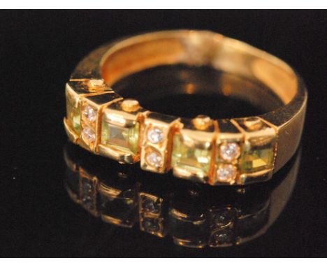 A modern 18ct peridot and diamond ring, four square cut peridot spaced by three pairs of brilliant cut diamonds, ring size K.