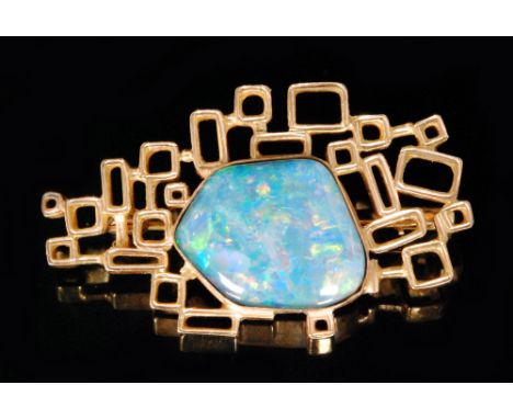 A modernist opal brooch, collar set opal within an openwork border of gold coloured squares and rectangles with bar fitting a