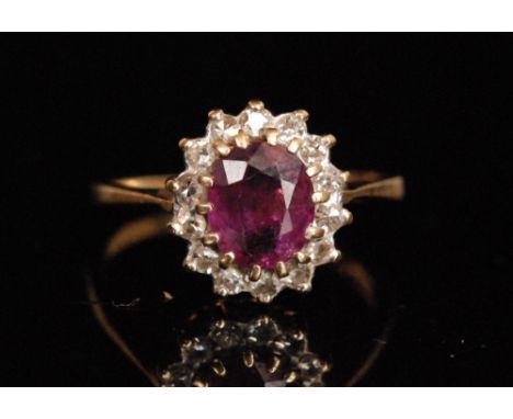A 9ct hallmarked ruby and diamond cluster ring, central oval ruby within a fourteen brilliant cut diamond surround, ring size