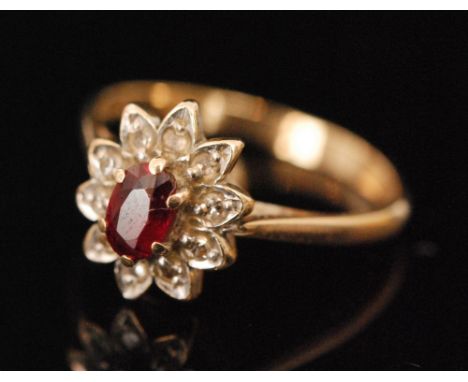 A hallmarked 9ct ruby and diamond cluster ring, oval cut ruby with diamond surround, knife edge shoulder, weight 1.8g, ring s