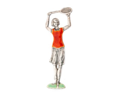 A 1930s brooch modelled as a female tennis player holding a racket aloft, red enamel decoration to vest and green detail to b