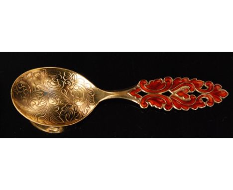 A Norwegian silver gilt and enamel spoon with oval foliate engraved bowl and pierced C scroll and leaf handle enameled in red