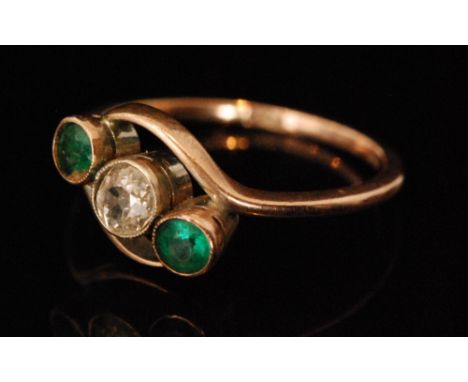 An early 20th Century 9ct three stone emerald and diamond ring, central old cut diamond flanked by emerald, all to a slight t