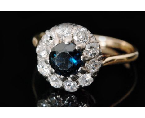 A mid 20th Century 18ct sapphire and diamond cluster ring, central circular claw set sapphire within a ten stone brilliant cu