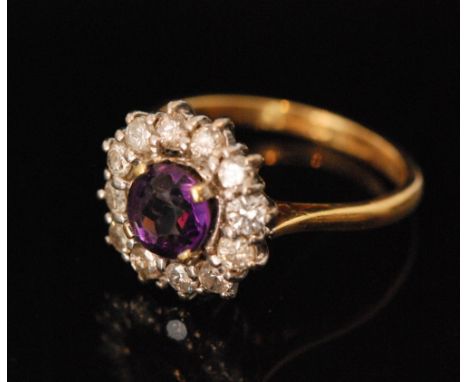 An 18ct hallmarked amethyst and diamond cluster ring, central claw set circular amethyst within a twelve stone brilliant cut 