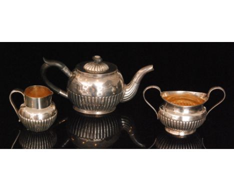 A hallmarked silver three piece bachelor tea service composed of tea pot, cream jug and sugar, each with half fluted decorati