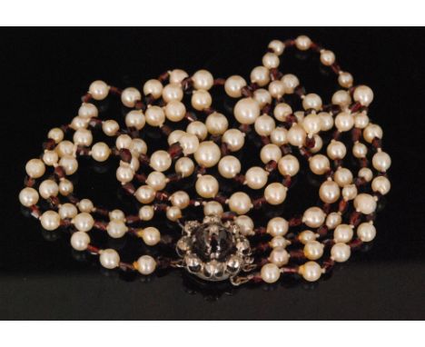 A garnet and cultured pearl three strand graduated necklace, each pearl spaced by a facet cut garnet bead to white metal clas