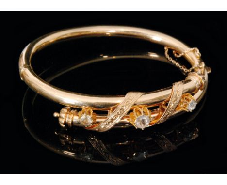 A 19th Century gold hinged bangle detailed with three old cut, claw set diamonds spaced by foliate engraved decoration, large