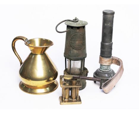 A mixed lot of metal ware comprising a brass jug, a miners lamp, a divers torch by Siege Gorman & Co. and a trench art nut cr