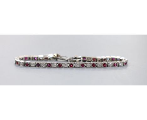 A modern white metal, twenty one stone ruby and twenty three stone diamond set line bracelet, 17.3cm, gross weight 12.5 grams