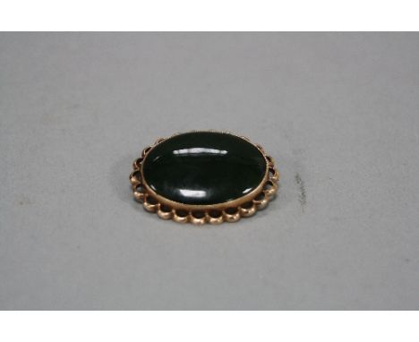 A MID TO LATE 20TH CENTURY NEPHRITE JADE BROOCH, oval cabochon measuring approximately 24mm x 18mm, miligraine set within a s