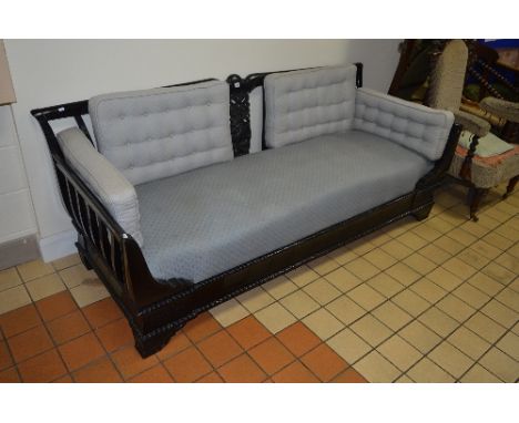 A LARGE EBONISED THREE SEATER SOFA, slatted back and arms with carved central splat and blue upholstery