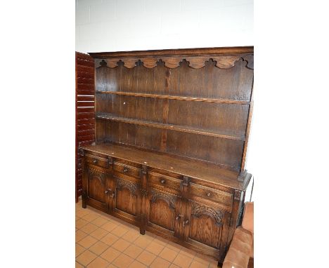 A LARGE OAK DRESSER, two shelf plate rack above four short drawers and four carved panelled doors, approximate size width 200