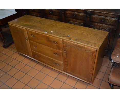 AN ERCOL ELM SIDEBOARD, with three central drawers on casters