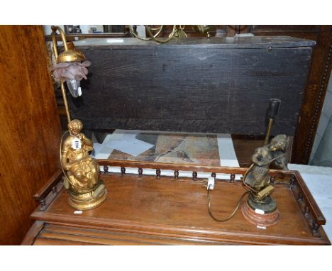 A GILT PAINTED TABLE LAMP OF A SEATED LADY READING, and bronzed table lamp of a girl, on a pink marble base (2)