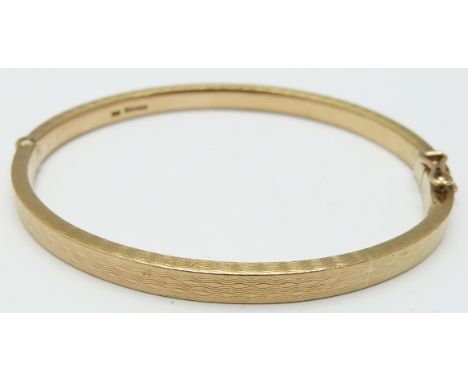 A 9ct gold bangle with raised textured detail, 30.9g