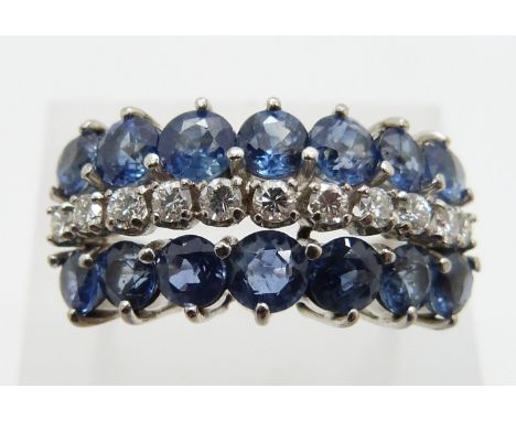 A 14k white gold ring set with a row of round cut diamonds and two rows of cornflower blue sapphires, 7.1g, size R