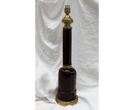 A ruby glass and brass table lamp, with a brass ogee shaped top above a octagonal column, the domed base of Dodecagon shape o