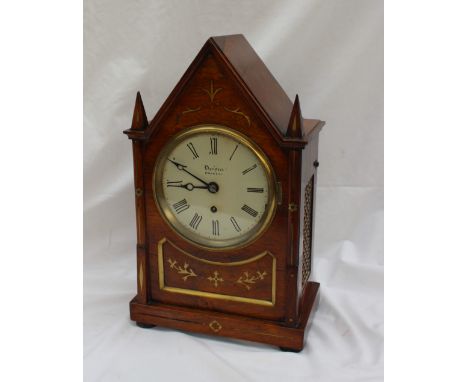 A Regency rosewood steeple mantle clock, with a pointed top the body inlaid with brass scrolls on flattened bun feet, the cir