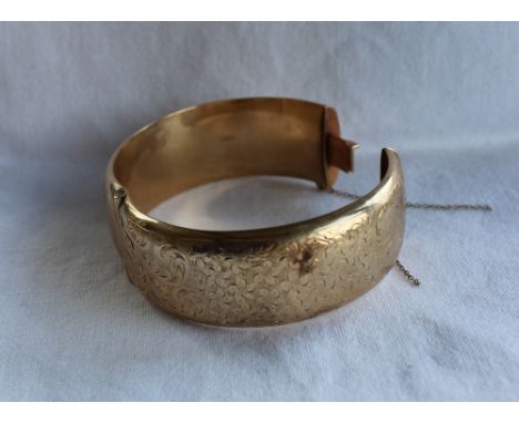 A 9ct yellow gold hinged bangle, with scrolling floral decoration, approximately 35.5 grams