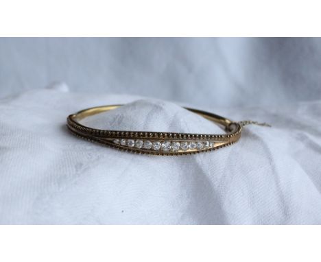 A Victorian diamond set hinged bangle set with thirteen round old cut diamonds to a yellow metal setting inscribed 29th April