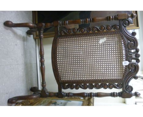 A late Victorian scroll carved, oak framed firescreen, set with a woven, split cane panel, on slender, ring turned, baluster 