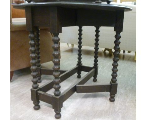 A 1920s dark stained oak gate leg table, the oval top raised on a bobbin turned and block underframe  28''h  30''w closed    