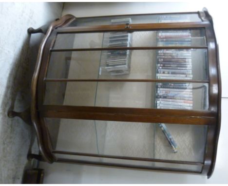 A 1950s walnut bow front display cabinet, having a central door, enclosing two glass shelves, raised on stubby cabriole legs 