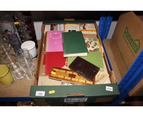 A box of various books and a cribbage board 