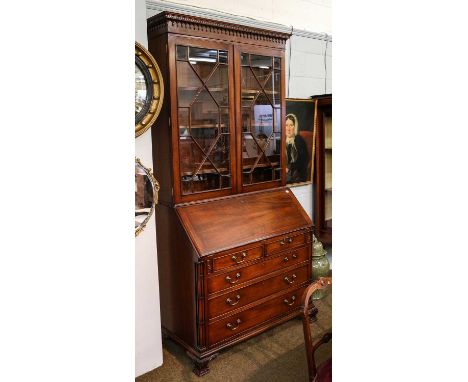 A George III style bureau bookcase, the moulded and dentil cornice above a pair of astragal glazed doors, over a lower sectio