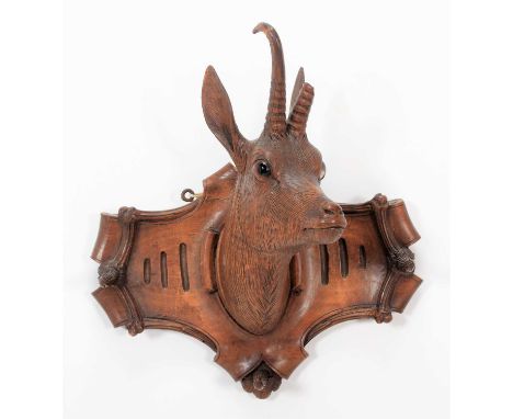 A Carved Black Forest Whip Rack, in the form of an Alpine Chamois head mount, the carved shield with three applied pointed ho