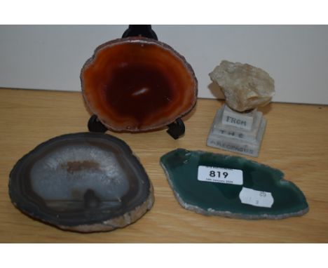 Three slices of polished agate in green orange and white colours along with an agate stone on a plinth from the Areopagus.