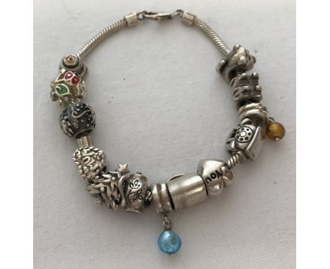 A modern silver snake chain charm bracelet with 13 silver charms.  Approx weight 46.9 g.
