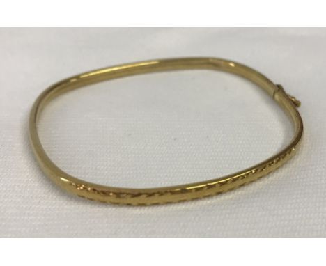 9ct gold bangle with safety clasp and decorative engraving to one side.  Weight approx 3.6g