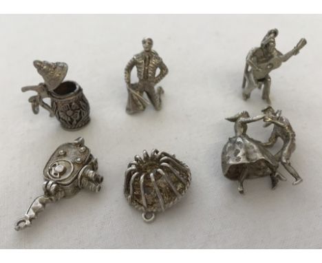 A collection of 6 vintage white metal  bracelet charms. Comprising a stein with lift up lid, a matador, a man playing a guita