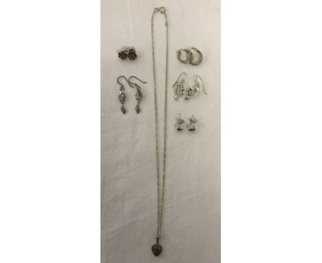 5 pairs of silver/white metal earrings and a silver pendant and chain. Some set with red stones. 