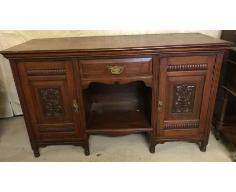 A Victorian mahogany sideboard with carved detail to front and original brass handles. 2 cupboards with interior shelves, cen