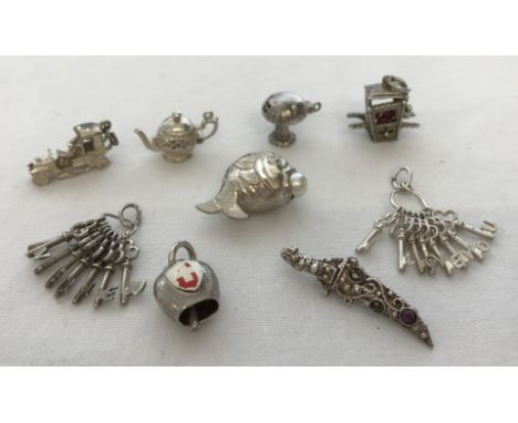 9 silver and white metal bracelet charms. Some with moving parts. Comprising a vintage car, a teapot with lift up lid, a toad