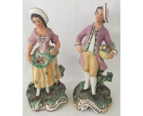 A pair of Victorian ceramic figurines of a man and woman holding baskets of fruit.  Approx. 20cm tall.