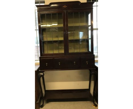 A mahogany 2 door display cabinet with leaded glass doors and 2 interior fabric lined shelves. Bottom half on cabriole legs w