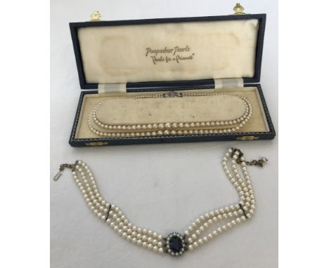 A boxed double string of Pompadour faux pearls with marcasite set clasp. Together with a faux pearl choker with central blue 