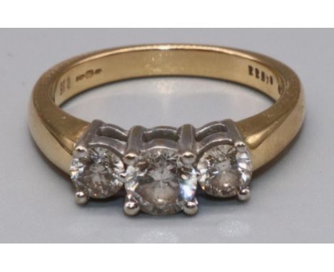 18ct yellow gold three stone diamond ring, the central brilliant cut diamond flanked by two smaller diamonds, in claw setting