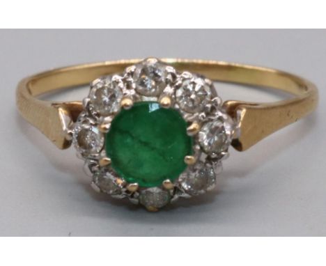 18ct yellow gold emerald and diamond cluster ring, the central circular faceted cut emerald surrounded by a halo of brilliant