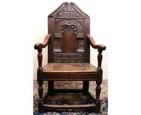 C17th style oak wainscot arm chair, arched panel back with scale carved angular top rail bearing dated 1633, solid seat on va