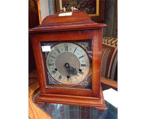 A George III style mahogany bracket clock, circular brass dial with Roman numerals, cherubic spandrels, the domed top with br