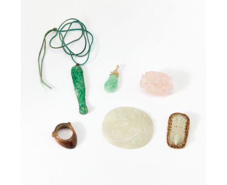 Comprising an openwork jade carving of a bird in mount, a celadon jade oval plaque, a jadeite pendants, a rose quartz badgers