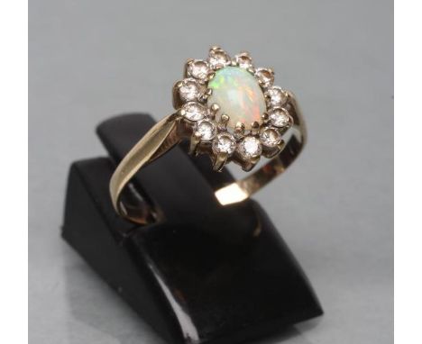 AN OPAL AND DIAMOND CLUSTER RING, the oval cabochon polished opal claw set to a border of small round brilliants and a plain 