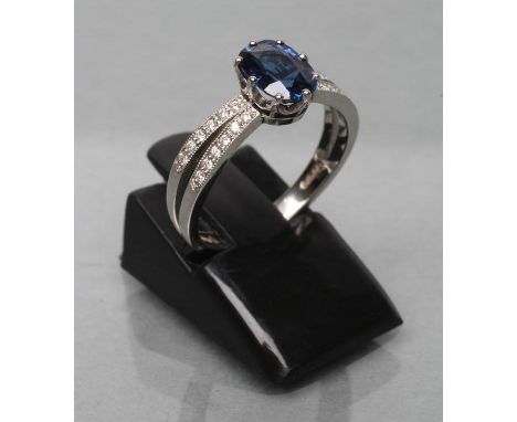 A CEYLON SAPPHIRE AND DIAMOND DRESS RING, the oval facet cut sapphire of 1.06cts, claw set to open point set small diamond sh